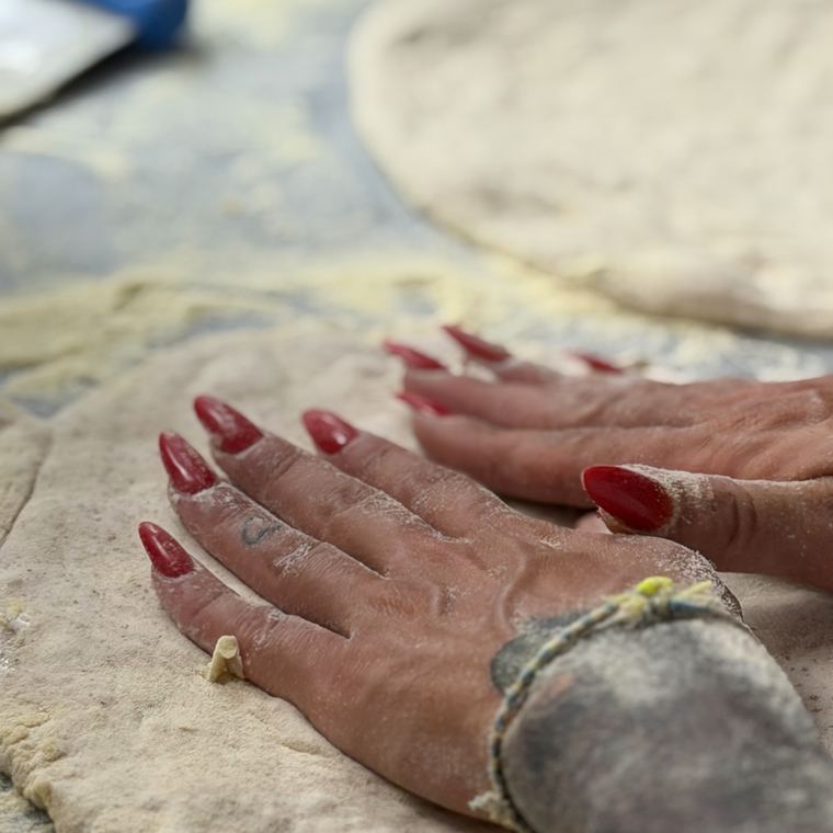 Le mani lavorano l’impasto sul banco infarinato